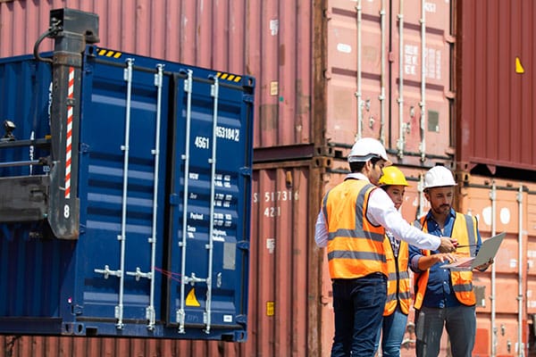 Hispanic man harbor worker talking on the walkie-talkie radio and control loading containers at container warehouse. container yard port of import and export goods