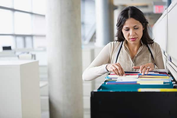 Businesswoman searching through a filing cabinet