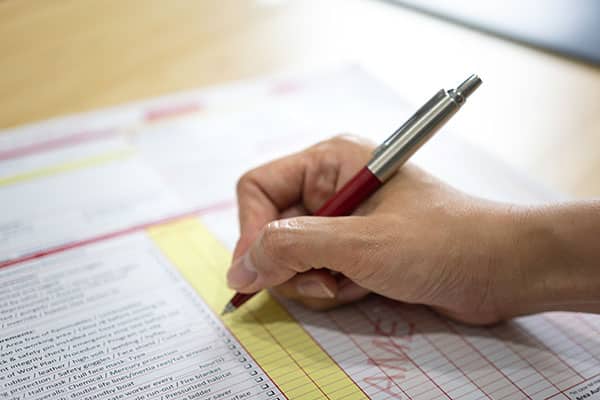 Action of safety officer is using a pen to marking checklist in